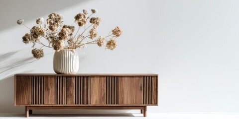 Dried flowers in vase on mid-century modern credenza against white wall