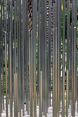 rury ze stali nierdzewnej ustawione pionowo, dekoracja ze stalowych rur w ogrodzie, group of stainless steel pipes arranged vertically like garden sculptures