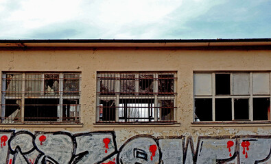 grafiti na ścianie zrujnowanego domu, obdrapana ściana zrujnowanego budynku z grafiti, graffiti on the wall of a ruined house,Old house with broken windows and graffiti, © kateej
