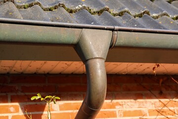 Old metallic gutter downspout system on brick wall