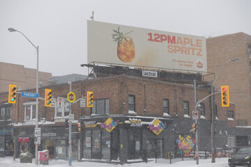 Obraz premium looking southeast to corner of Parkside Dr and Bloor St W with rooftop billboard and shop fronts during a snow storm on 2026-01-15 in Toronto