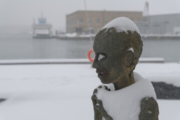 Naklejka premium close-up of Child Emigrant created by Irish artist Rowan Gillespie part of The Arrival, set beside the old Canada Malting silos on Eireann Quay, Toronto, during winter storm on 2026-01-15