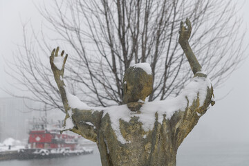 Naklejka premium The Jubilant Man created by Irish artist Rowan Gillespie part of The Arrival, set beside the old Canada Malting silos on Eireann Quay, Toronto, during winter storm on 2026-01-15