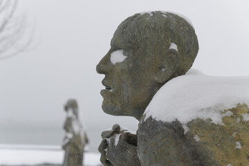 Naklejka premium left profile of Apprehensive Man created by Irish artist Rowan Gillespie part of The Arrival, set beside the old Canada Malting silos on Eireann Quay, Toronto, during winter storm on 2026-01-15