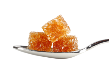 Brown sugar cubes on silver spoon against black background