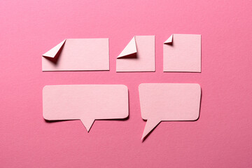 Speech bubbles and paper memo notes with folded dog-ear earmark and copy space for text on pink...