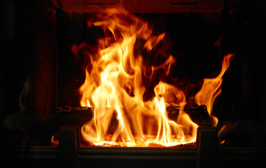 Fototapeta premium Fire burns brightly in a fireplace during the evening in a cozy home setting