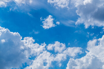 Obraz premium Photograph of airy white clouds against a blue sky, the edges of which are illuminated by lateral sunlight. Weather phenomena, synoptic forecasts. Blank for artworks