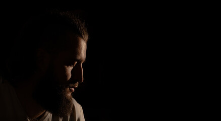 attractive dramatic middle adult age man portrait profile face with Greek nose and facial hair beard black background low key lighting advertising copy space