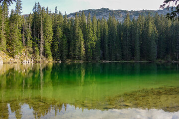 sunset reflects over green surface of Zminje lake in Durmitor National Park, Zabljak, Montenegro