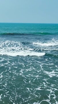 Vast expanse of turquoise ocean water with foamy waves rolling Vertical video