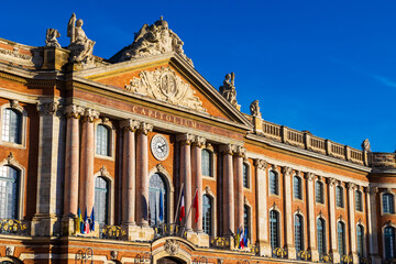 Obraz premium Façade of the Capitole, Toulouse city hall, illuminated by the sun in front of dark silhouettes