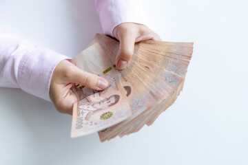Money, Cash, Wealth, Hands holding a large amount of Thai baht banknotes, symbolizing cash, wealth, and financial success, close-up
