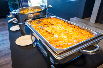 Chicken lasagna in a metal tray at a buffet station
