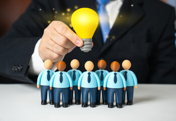 A lightbulb of an idea shines over a team of office workers. A leader inspires his subordinates. A project manager. Creative leadership concept, motivation and vision. Innovation culture