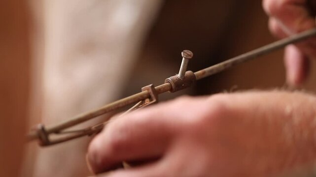 Extreme close up of a sculptor's hands using metal calipers to measure a clay sculpture. The artist checks the dimensions with high precision while working in his art studio.

