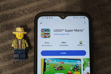Fototapeta premium LEGO Super Mario app displayed on a smartphone next to a LEGO minifigure