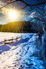 rustic wooden fence through snow covered hill. day and night time change concept. beautiful view in...
