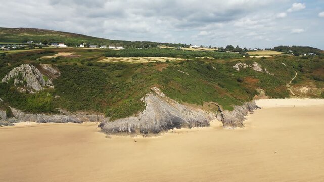 Drone footage capturing the sweeping sandy beach and turquoise waters of Oxwich Bay on the Gower Peninsula in South Wales, filmed on a bright summer day with clear skies and calm seas.