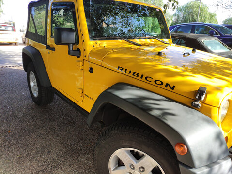 Cagliari, Italy - January 15, 2026: Yellow Jeep Rubicon parked outdoors with clear blue sky and trees in the background, showcasing its rugged design and off-road capabilities