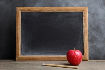 Empty chalkboard with wooden frame and red apple on desk