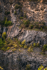 Panoramic landscape of the flooded Velka Amerika limestone quarry featuring turquoise water, steep rocky cliffs, and winding hiking trails under a dramatic cloudy sky in the Czech Republic.