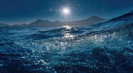 Water-level view bright sun on ocean with mountains, blue and shining