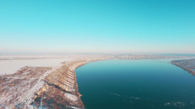 FPV drone aerial shot. Beautiful nature landscape in winter of the Dniester River with a mountain bank and clear blue sky. Moldova, Europe