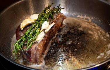 The chef cooks delicious meal on stove. The cook fries piece of juicy beef meat on frying pan with...