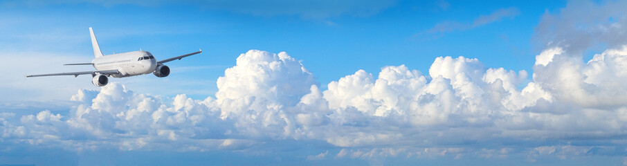 White airplane flying across blue sky with clouds