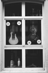 Guitars displayed in music shop window in black and white
