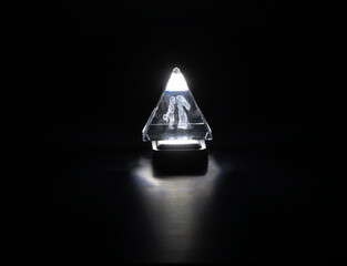 Consecrated glass prism pyramid isolated on black background
