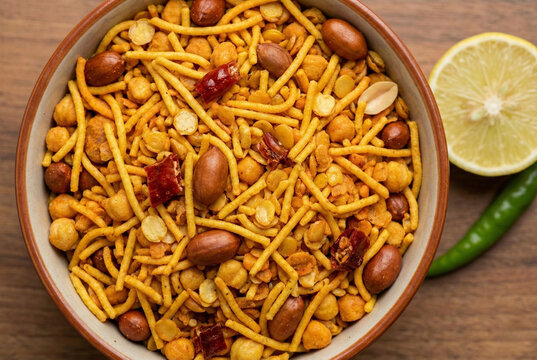 Traditional spicy Bengali Chanachur snack mix with peanuts and fried lentils in bowl with lemon and chili