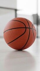 Fototapeta premium Orange basketball resting on a light wooden floor with blurred bright background