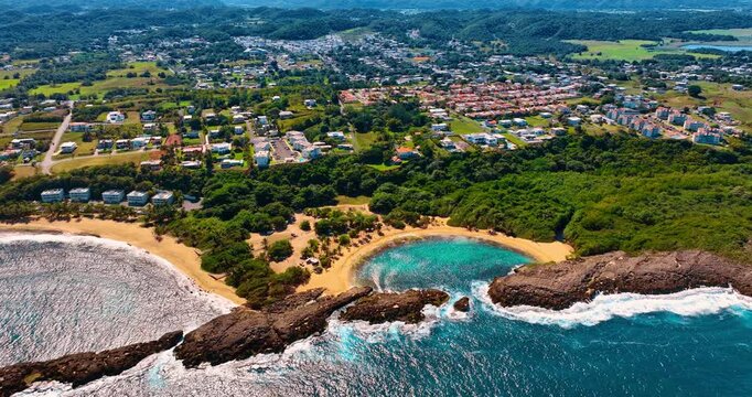 Iconic beaches with clear turquoise water. Aerial view on the stunning Mar Chiquita Beach in Manati, Puerto Rico. Cityscape with lush greenery at backdrop.