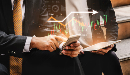 Business professionals collaborate on financial strategies using smartphone and tablet, analyzing evolving market data and trends amidst digital graphics in a modern environment. Scalp