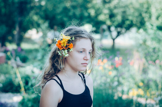 portrait of teenage girl with orange and yellow flowers in hair