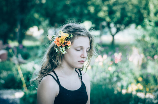 emotional portrait of teenage girl with orange and yellow flowers in hair