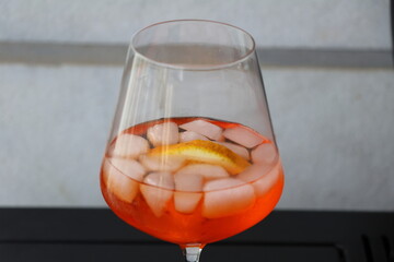 Aperol spritz cocktail with lemon and ice in a glass