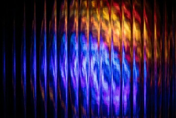 an abstract display of vertical lines illuminated with vibrant blue purple orange and yellow light creating a blurred dynamic visual texture