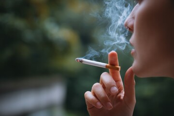 Close-up of female smoking outdoors with blurred background