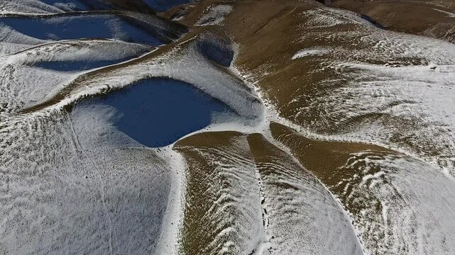 Drone top down aerial view of USA mountain ranges with first seasonal snow covering peaks. Winter landscape shows rugged ridges, cold weather and fresh snowfall across wilderness