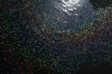 Festive black and silver holographic glitter texture with rainbow highlights.