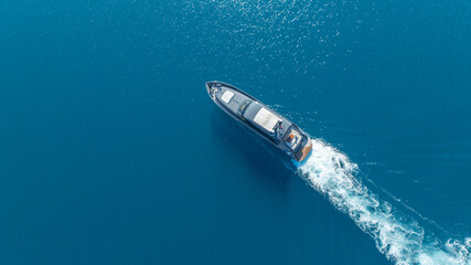 Seafaring Vessel: Aerial perspective of a sleek vessel navigating across a vast, tranquil expanse of ocean, leaving a wake. © ALPSARAL