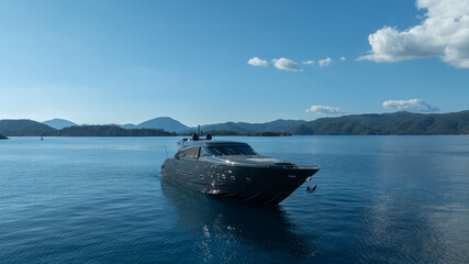 Obraz premium Luxury Yacht on Serene Waters: A sleek, modern yacht cruises effortlessly on calm, crystal-clear waters, reflecting the bright blue of the sky and offering a vision of pure luxury and tranquility.