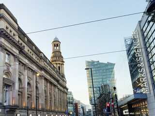 Naklejka premium Busy Manchester Cross street scene featuring historic architecture and contemporary shopping center UK