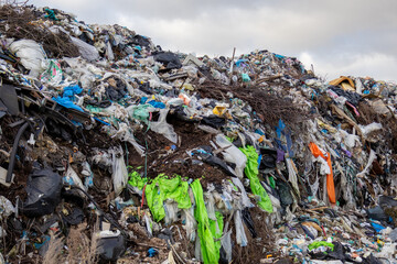 Obraz premium Large landfill filled with piles of garbage and various waste materials under a cloudy sky. Pollution fills the area with debris