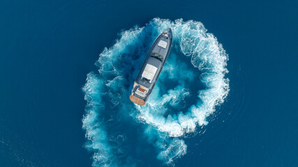 Luxury Vessel's Azure Dance: A sleek vessel carves a dynamic spiral through cerulean waters, leaving a mesmerizing trail. The boat is an emblem of modern maritime, embodying both power and elegance.