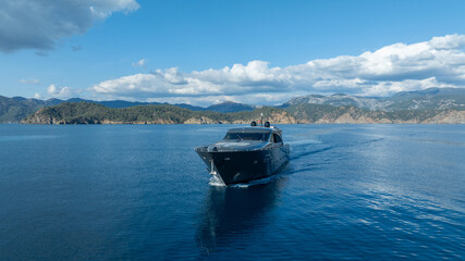 Yacht on the horizon: A sleek motor yacht cuts through the pristine waters under a vibrant blue sky, epitomizing luxury and freedom.