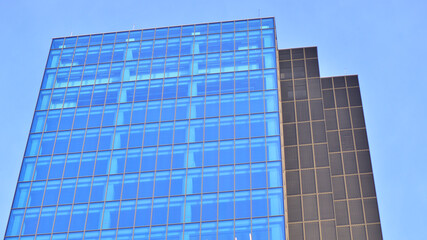 A modern tall building made of steel and glass, housing offices and financial institutions. Glass wall on the facade of the building.